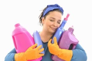 Happily smiling eyes shut maid hugging a bunch of cleaning produ