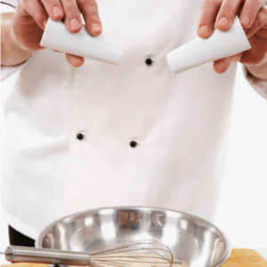 A chef adding salt and pepper in a bowl